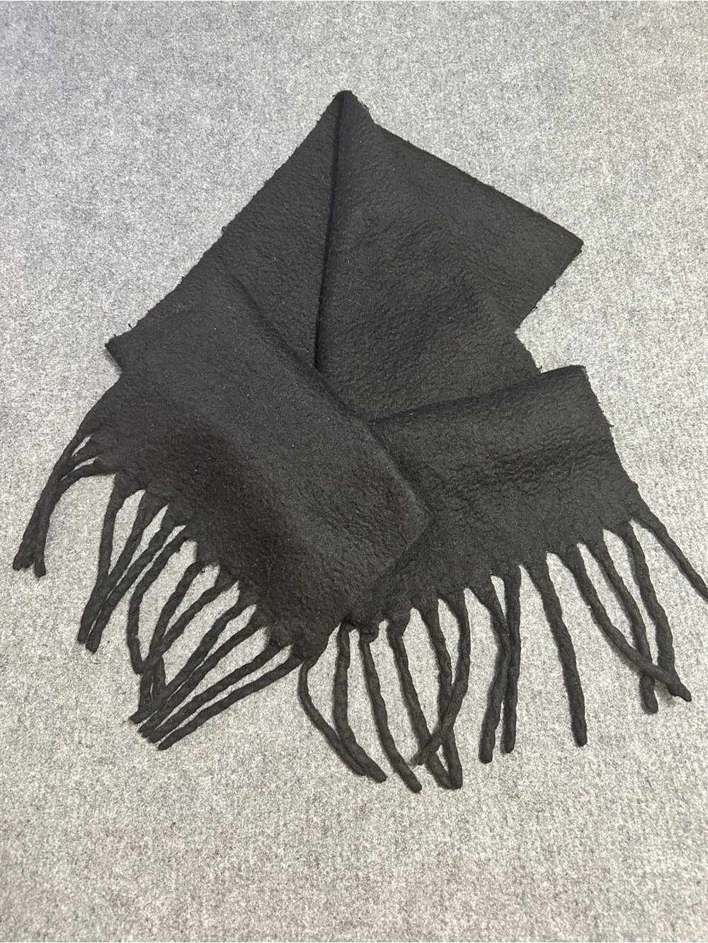 Black textured fringe scarf with a soft, fuzzy finish and thick tassel ends.
